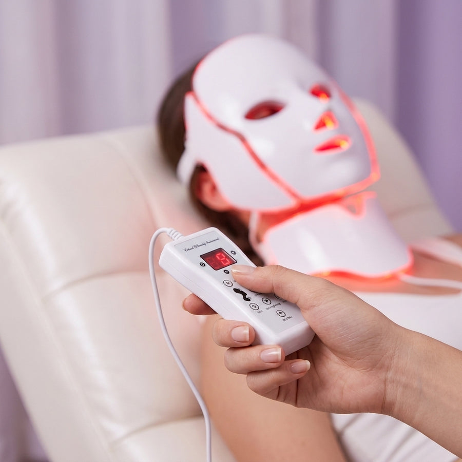Mano sujetando el mando de la mascarilla LED Dermiq con la pantalla encendida