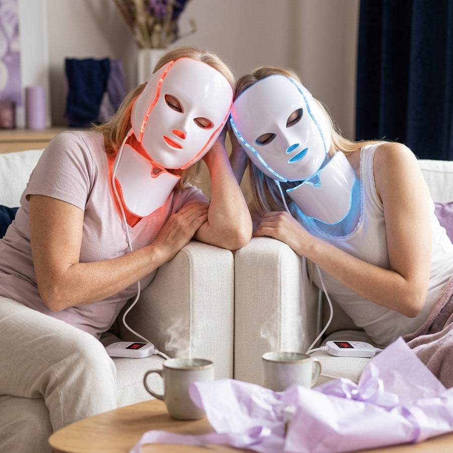 Madre e hija en el sofá con dos mascarillas LED Dermiq, una en luz roja y otra en azul
